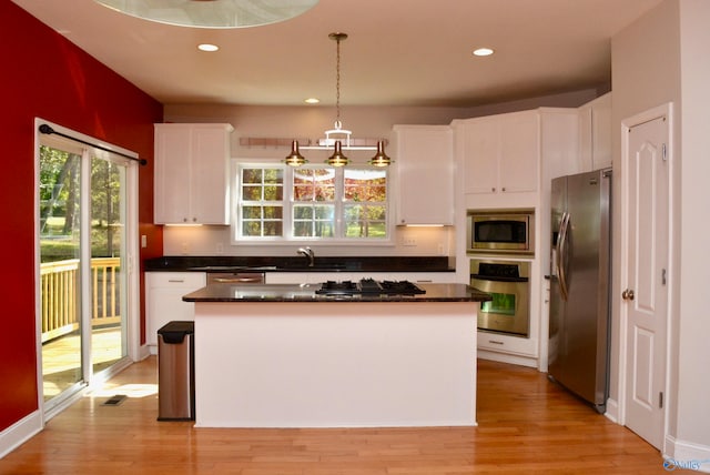 kitchen featuring a kitchen island, light hardwood / wood-style flooring, hanging light fixtures, white cabinets, and appliances with stainless steel finishes