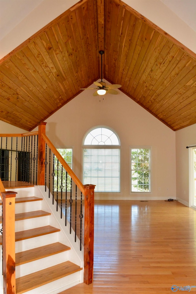 staircase with hardwood / wood-style flooring, a healthy amount of sunlight, and vaulted ceiling with beams