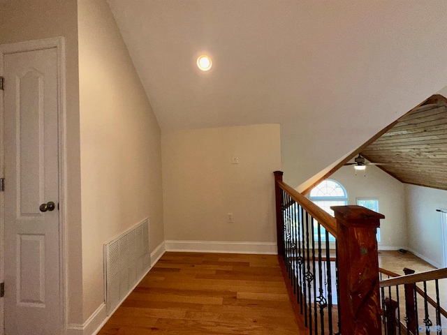 corridor with hardwood / wood-style floors and vaulted ceiling