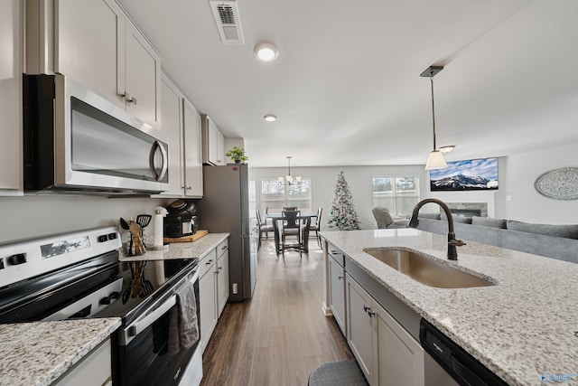 kitchen with white cabinets, sink, decorative light fixtures, light stone counters, and stainless steel appliances