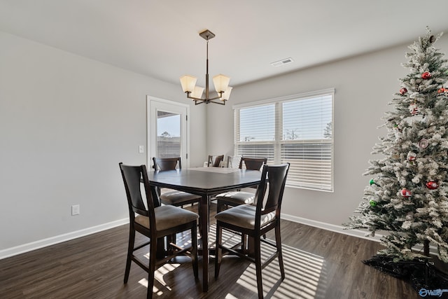 dining area with dark wood-type flooring and a notable chandelier