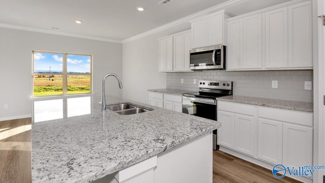 kitchen with stainless steel appliances, hardwood / wood-style floors, sink, an island with sink, and white cabinetry