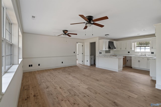 unfurnished living room with light wood-type flooring, sink, ceiling fan, and ornamental molding