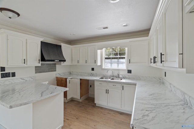 kitchen featuring light hardwood / wood-style floors, sink, kitchen peninsula, range hood, and white cabinets