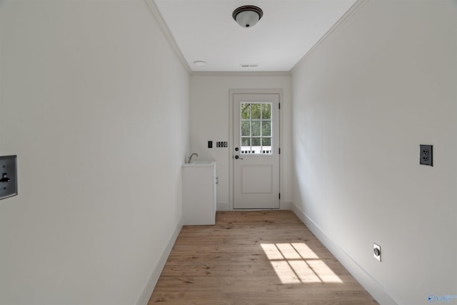 doorway to outside featuring light hardwood / wood-style floors, sink, and ornamental molding