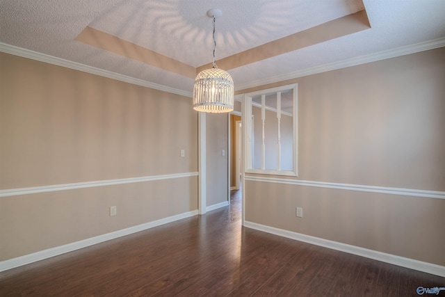 spare room featuring ornamental molding, a textured ceiling, dark hardwood / wood-style floors, and a tray ceiling