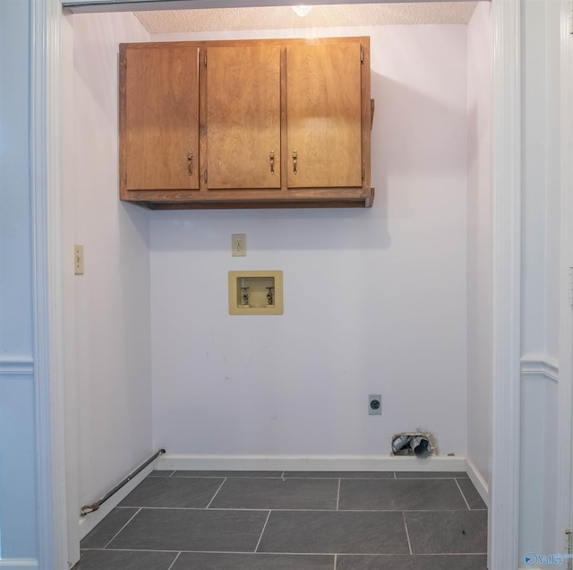 laundry room featuring hookup for an electric dryer, washer hookup, cabinets, and dark tile patterned flooring