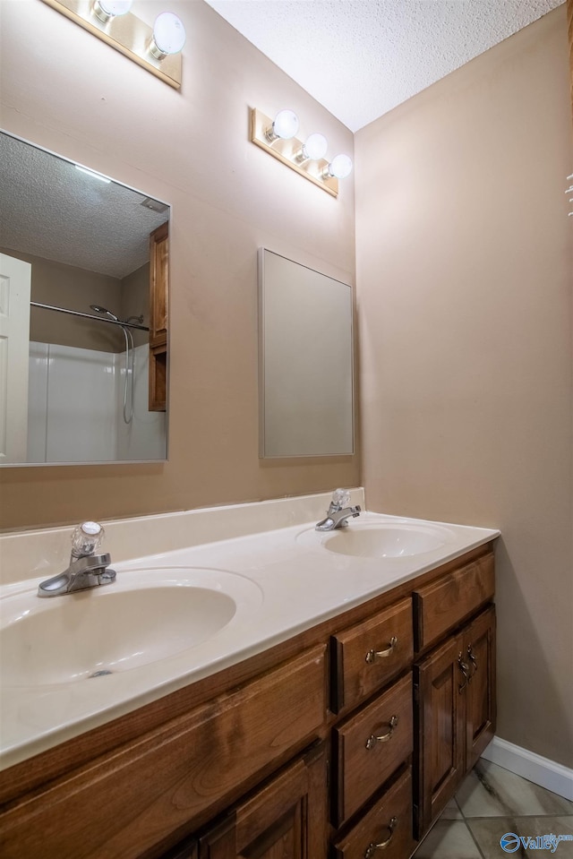 bathroom featuring vanity, a textured ceiling, a shower, and tile patterned flooring