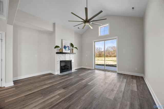 unfurnished living room featuring baseboards, ceiling fan, dark wood-type flooring, high vaulted ceiling, and a high end fireplace