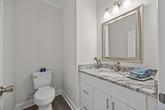 bathroom featuring toilet, baseboards, wood finished floors, and vanity