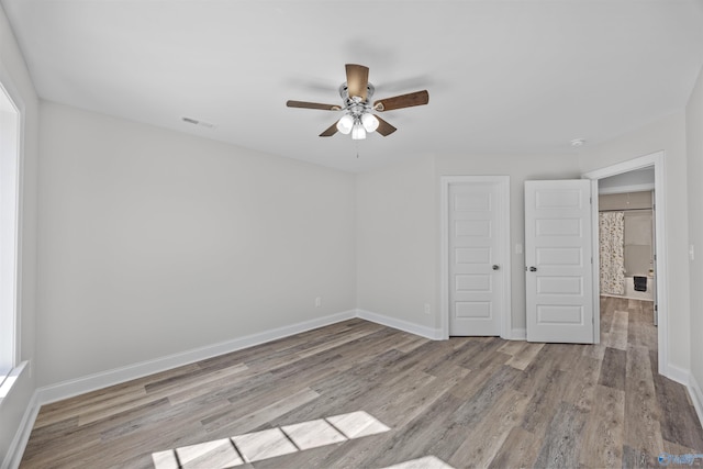 unfurnished bedroom featuring ceiling fan, wood finished floors, visible vents, and baseboards