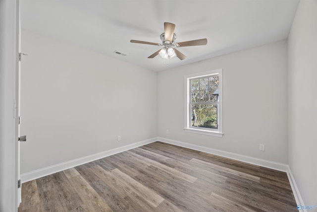 empty room featuring a ceiling fan, visible vents, baseboards, and wood finished floors