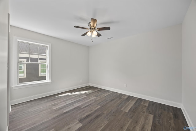 empty room featuring dark wood-type flooring, visible vents, ceiling fan, and baseboards