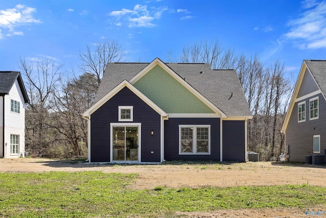 back of house featuring central AC and roof with shingles