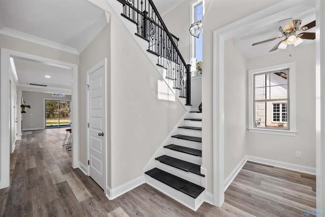 stairs with crown molding, baseboards, and wood finished floors