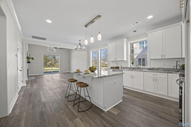 kitchen with white cabinets, open floor plan, visible vents, and a center island