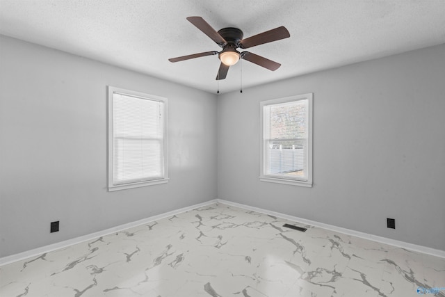 empty room with ceiling fan and a textured ceiling