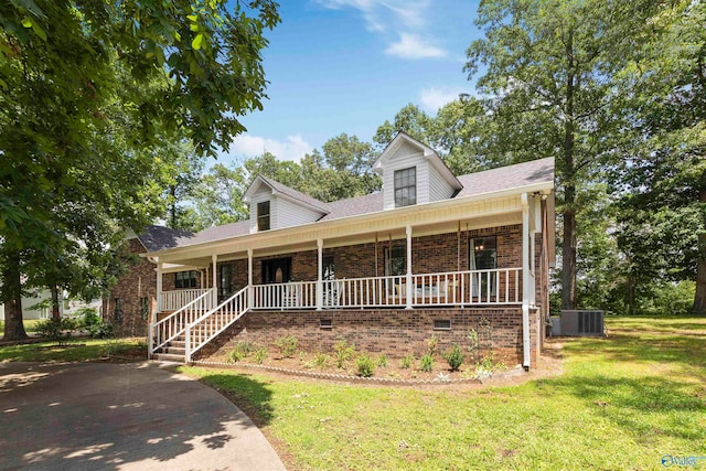 new england style home with covered porch, central AC, and a front lawn