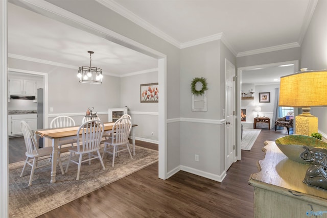 dining area with ornamental molding, an inviting chandelier, and dark wood-type flooring