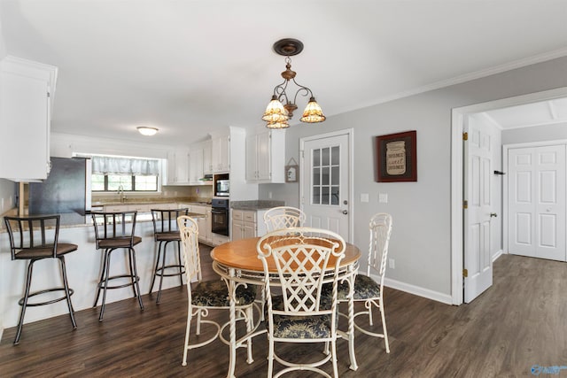 dining space with a notable chandelier, dark hardwood / wood-style floors, ornamental molding, and sink