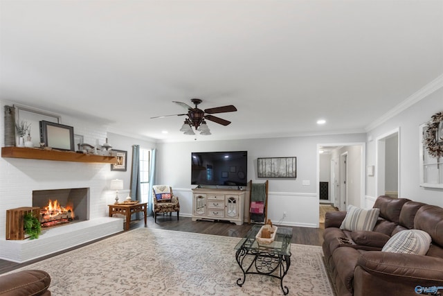 living room featuring dark hardwood / wood-style floors, a brick fireplace, ceiling fan, and ornamental molding