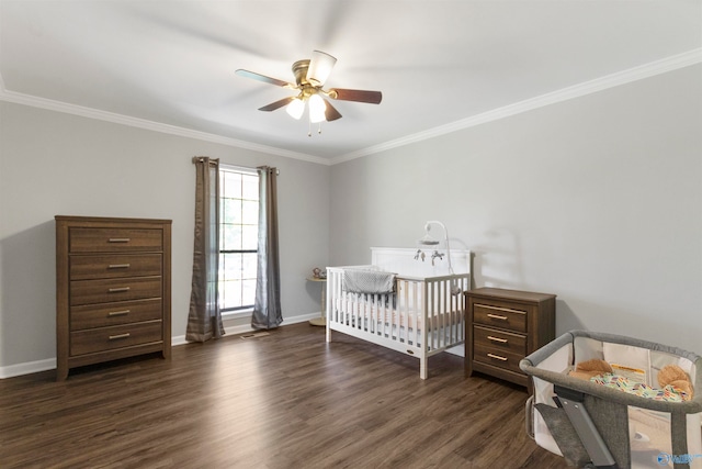 bedroom with a nursery area, crown molding, ceiling fan, and dark wood-type flooring