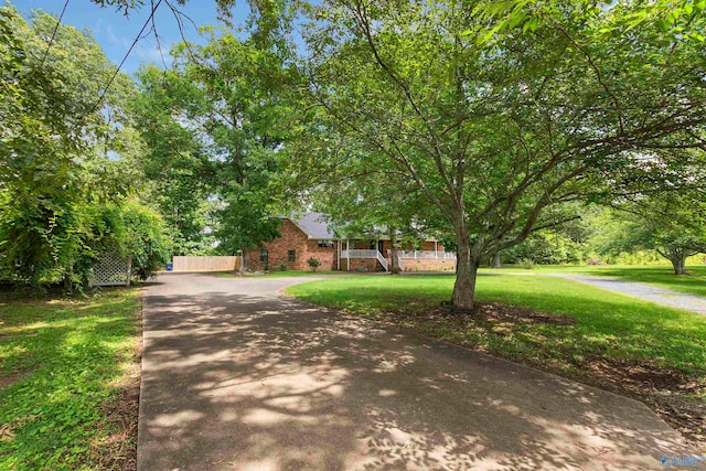 view of property hidden behind natural elements featuring a front lawn