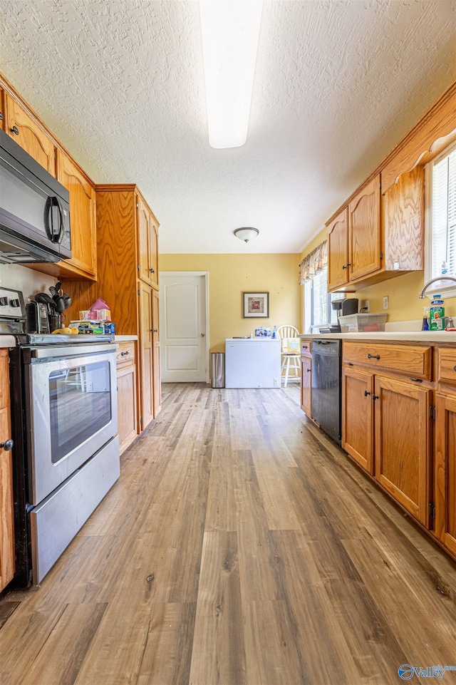 207 Sharp Dr, Gadsden, AL 35903 - kitchen featuring stainless steel electric range, black microwave, dishwasher, light wood-type flooring, and light countertops