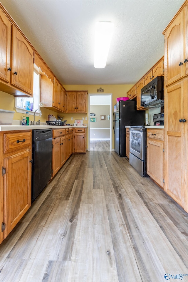 207 Sharp Dr, Gadsden, AL 35903 - kitchen with black appliances, light wood-style floors, light countertops, a textured ceiling, and a sink