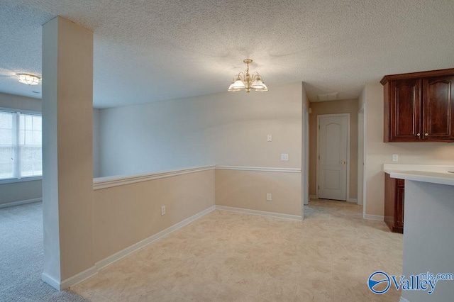 unfurnished dining area with a chandelier and a textured ceiling