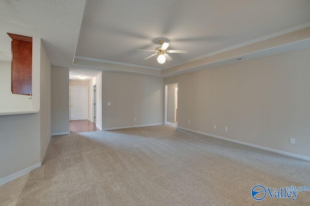 unfurnished room with ceiling fan, a tray ceiling, light colored carpet, a textured ceiling, and ornamental molding