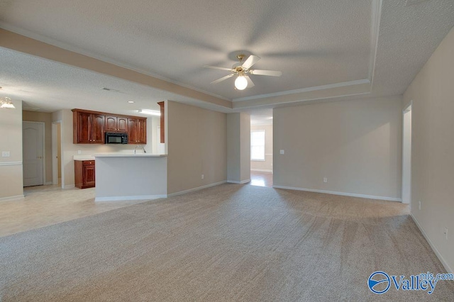 unfurnished living room featuring ceiling fan with notable chandelier, a textured ceiling, a raised ceiling, light colored carpet, and crown molding