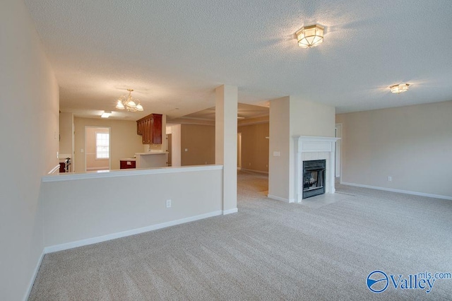 unfurnished living room with light carpet, an inviting chandelier, and a textured ceiling