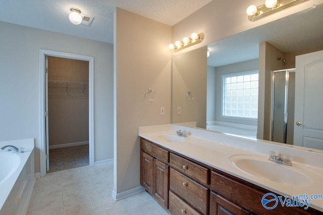 bathroom featuring a textured ceiling, separate shower and tub, and vanity