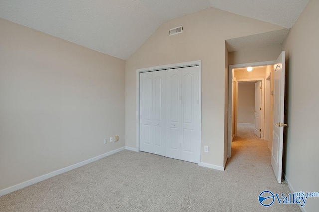 unfurnished bedroom with a closet, lofted ceiling, and light colored carpet