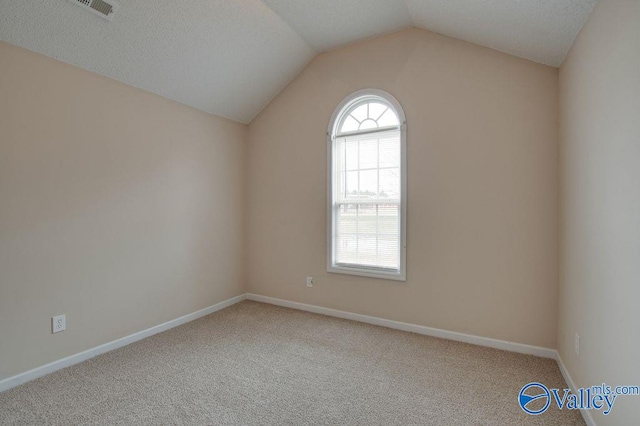 carpeted spare room with vaulted ceiling