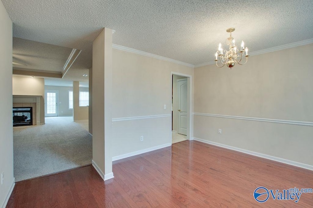 empty room featuring a textured ceiling, a chandelier, ornamental molding, and a tile fireplace