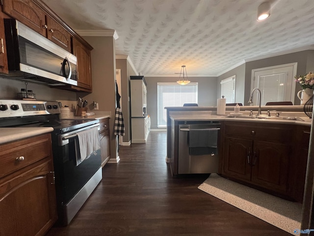 kitchen featuring dark wood finished floors, crown molding, appliances with stainless steel finishes, and a sink