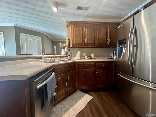 kitchen featuring visible vents, ornamental molding, a sink, dark wood finished floors, and stainless steel appliances