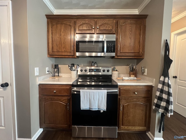 kitchen featuring dark wood-type flooring, light countertops, ornamental molding, brown cabinets, and stainless steel appliances