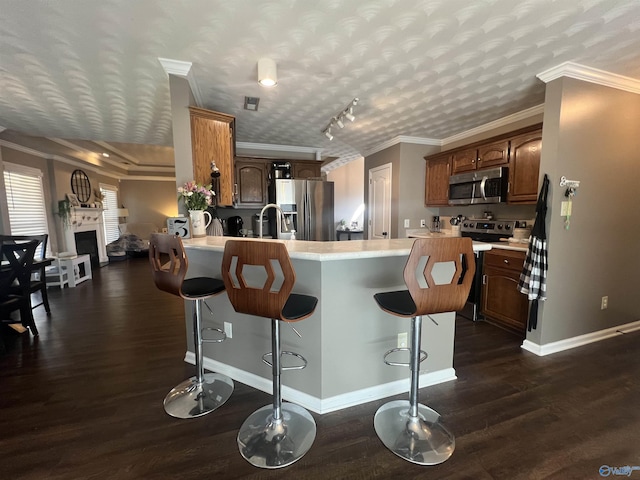 kitchen with a peninsula, stainless steel appliances, light countertops, and dark wood-style flooring