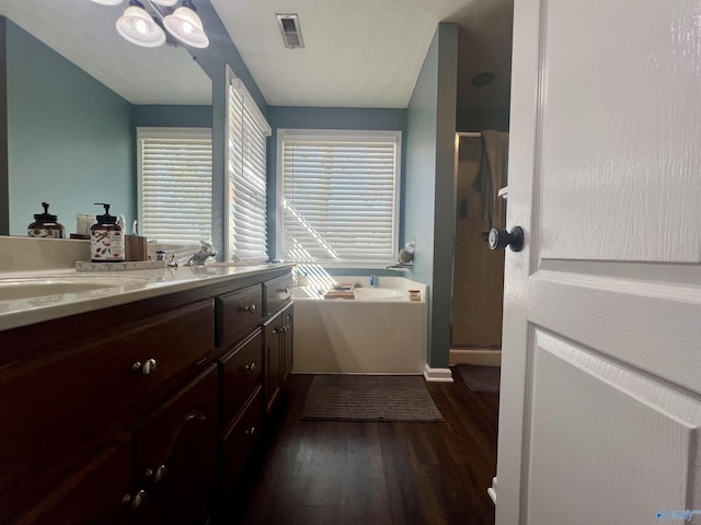 bathroom with visible vents, a stall shower, wood finished floors, a bath, and vanity