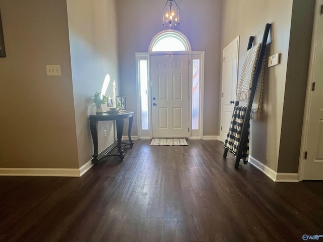 foyer featuring a notable chandelier, dark wood-type flooring, and baseboards