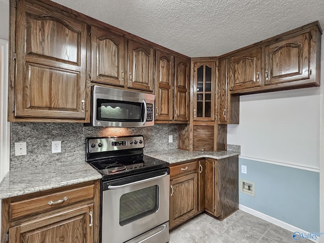 kitchen with light tile patterned flooring, stainless steel appliances, and decorative backsplash