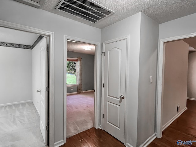 corridor with wood-type flooring and a textured ceiling