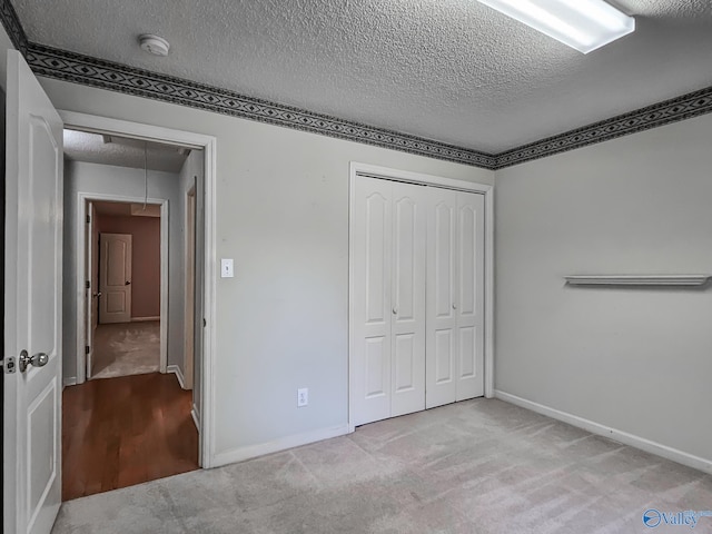 unfurnished bedroom featuring a textured ceiling, light carpet, and a closet