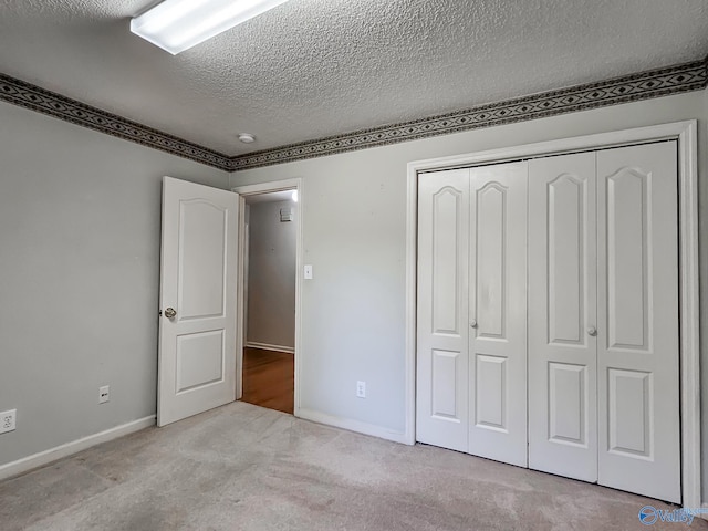 unfurnished bedroom with light carpet, a textured ceiling, and a closet