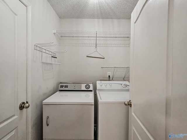 laundry area with a textured ceiling and washing machine and dryer