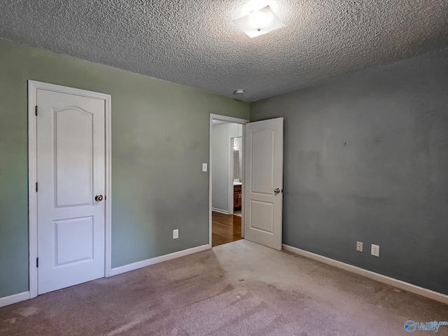 unfurnished bedroom featuring a textured ceiling and light colored carpet