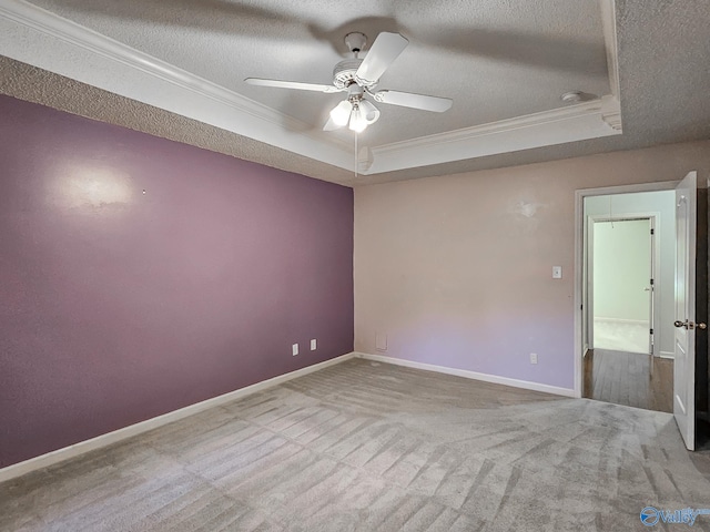 carpeted empty room with ornamental molding, ceiling fan, a raised ceiling, and a textured ceiling